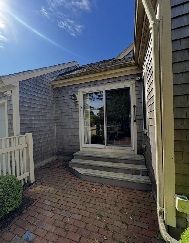 Gray, weathered cedar shingles and dirty brick patio before washing